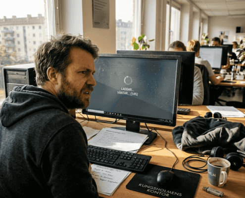 En kontorsanställd som sliter sitt hår över en dator som segar sig fram.