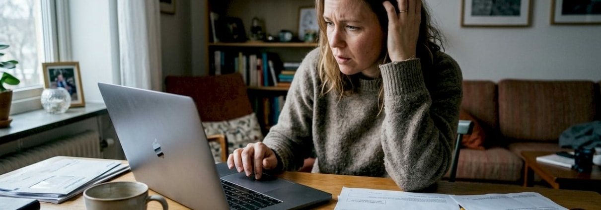 Kvinna kämpar med datorproblem hemma.